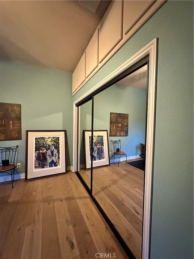 hall with light wood-style floors, visible vents, and baseboards