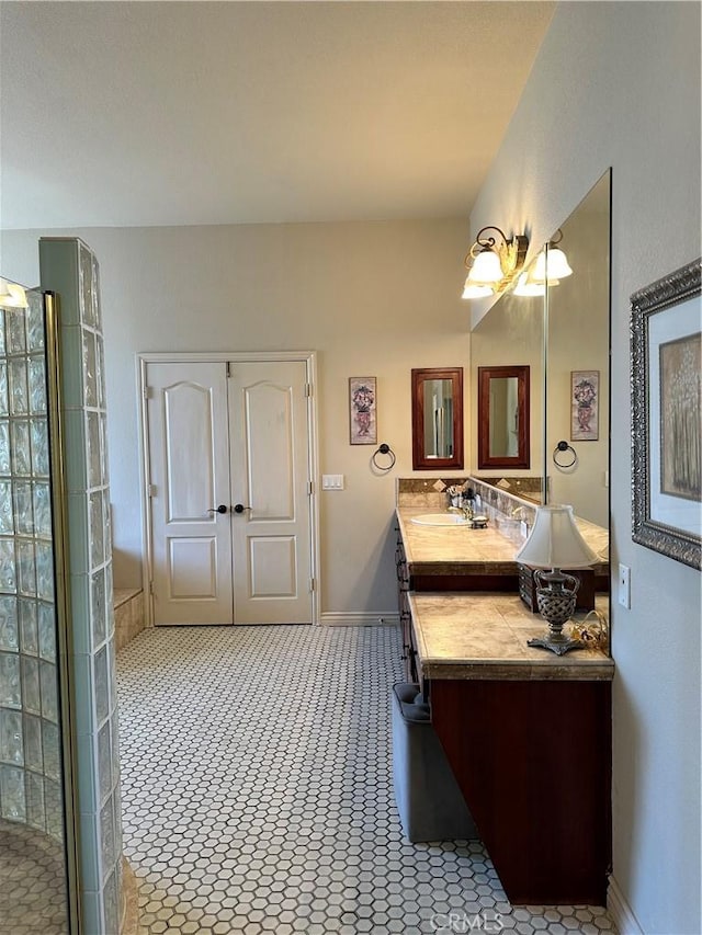 bathroom with baseboards, a tile shower, tile patterned flooring, and vanity