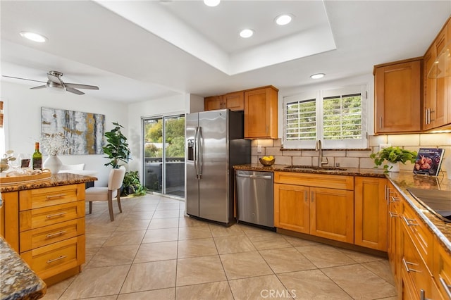 kitchen featuring stainless steel appliances, a healthy amount of sunlight, backsplash, and a sink