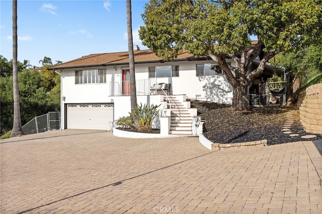 view of front of home featuring a garage, stairway, stucco siding, and decorative driveway