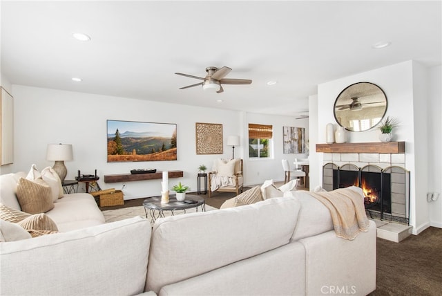 carpeted living area featuring a ceiling fan, recessed lighting, a warm lit fireplace, and baseboards