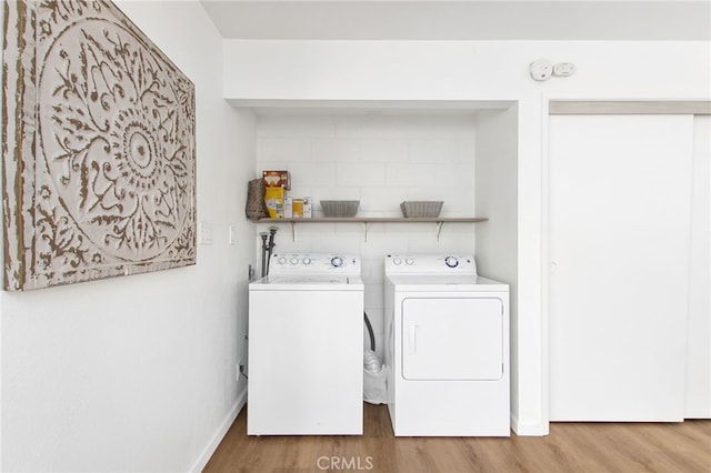clothes washing area with wood finished floors, washer and clothes dryer, laundry area, and baseboards