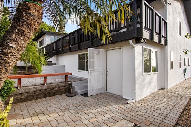 back of property featuring stucco siding, a balcony, and a patio