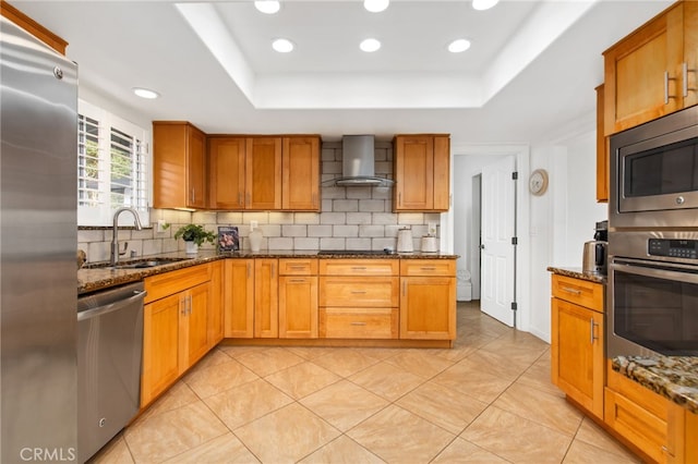 kitchen with recessed lighting, a sink, stainless steel appliances, tasteful backsplash, and wall chimney range hood