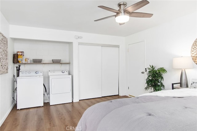 bedroom with wood finished floors, independent washer and dryer, a closet, baseboards, and a ceiling fan