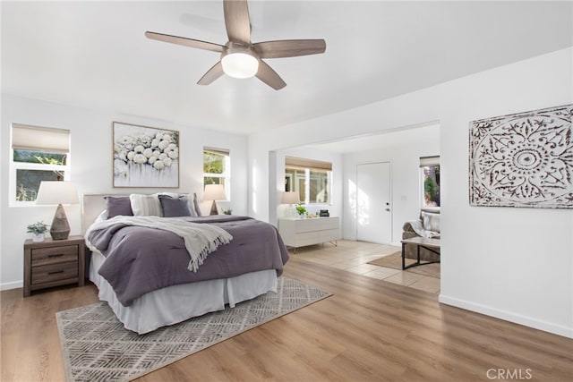 bedroom with a ceiling fan, wood finished floors, and baseboards