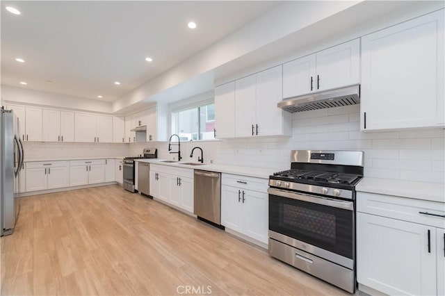 1444 W 37th St, Los Angeles, CA 90018 - kitchen with under cabinet range hood, decorative backsplash, light countertops, white cabinets, and appliances with stainless steel finishes