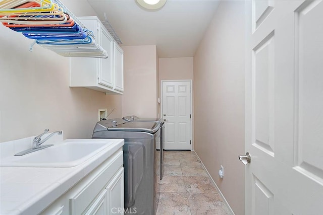 washroom with a sink, stone finish flooring, baseboards, washer and dryer, and cabinet space
