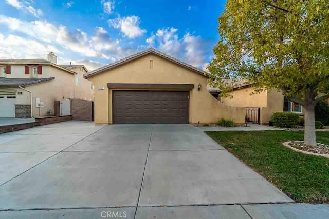 view of front of property featuring fence, stucco siding, driveway, and an attached garage