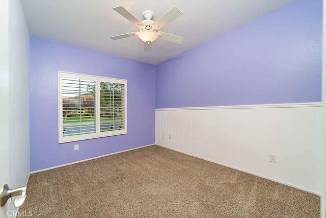 spare room with wainscoting, ceiling fan, and carpet flooring