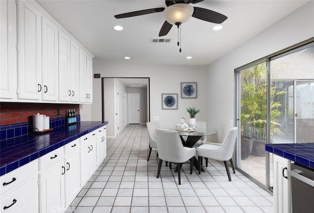 kitchen with tile counters, white cabinets, visible vents, and stainless steel dishwasher