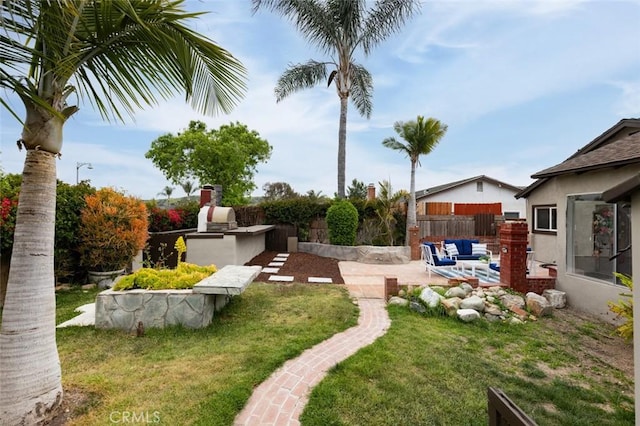 view of yard featuring a patio area, fence, and an outdoor kitchen