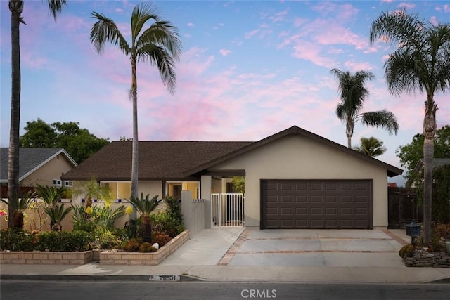 view of front of house featuring an attached garage, stucco siding, driveway, and fence