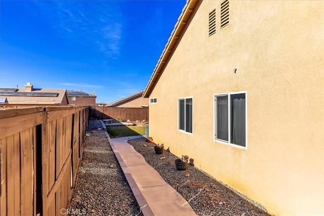 view of side of property with fence and stucco siding