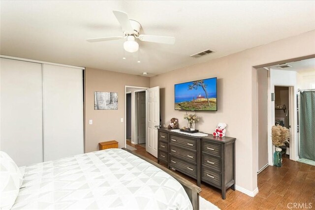 bedroom with a closet, ceiling fan, visible vents, baseboards, and wood finished floors