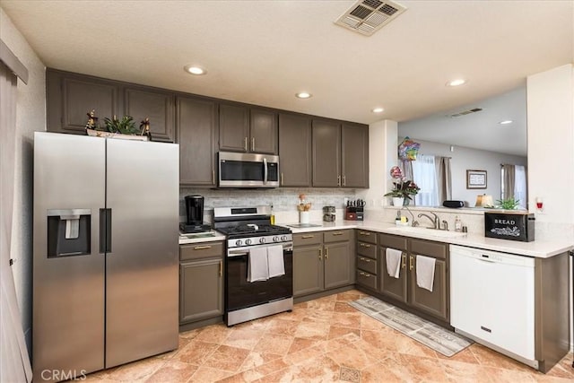 kitchen featuring tasteful backsplash, appliances with stainless steel finishes, light countertops, a sink, and visible vents
