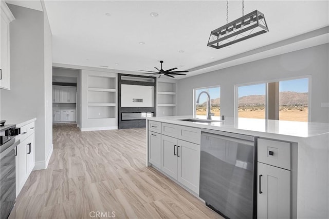 kitchen with stainless steel dishwasher, a sink, ceiling fan, and light countertops