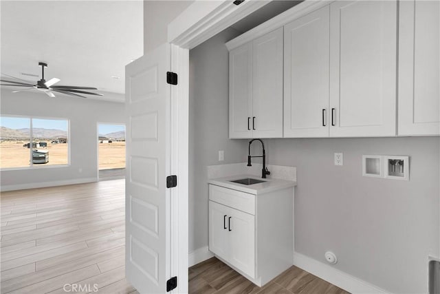 laundry room featuring cabinet space, washer hookup, a sink, a ceiling fan, and light wood-type flooring
