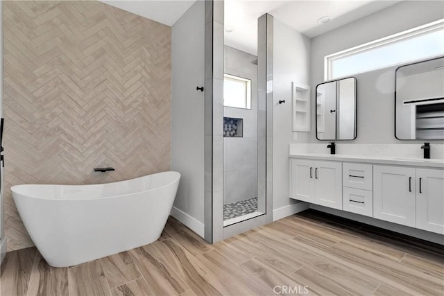 bathroom with double vanity, wood finished floors, a soaking tub, a shower stall, and a sink