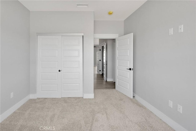 unfurnished bedroom with baseboards, a closet, carpet flooring, and visible vents