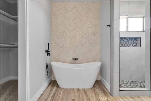 bathroom featuring baseboards, a tile shower, and a soaking tub