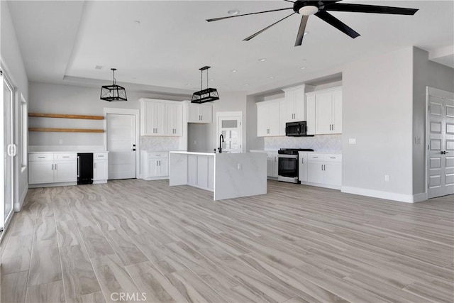 kitchen with gas stove, backsplash, black microwave, and white cabinetry