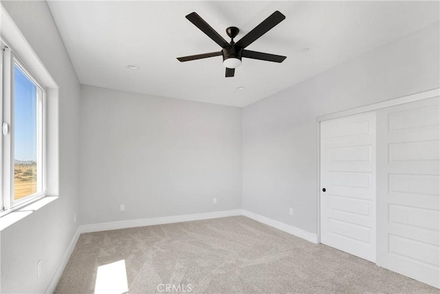 unfurnished bedroom featuring baseboards, multiple windows, a closet, and light colored carpet