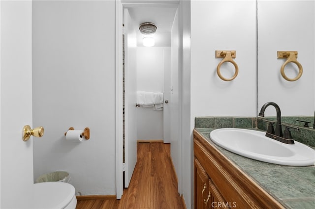 bathroom with toilet, vanity, and wood finished floors