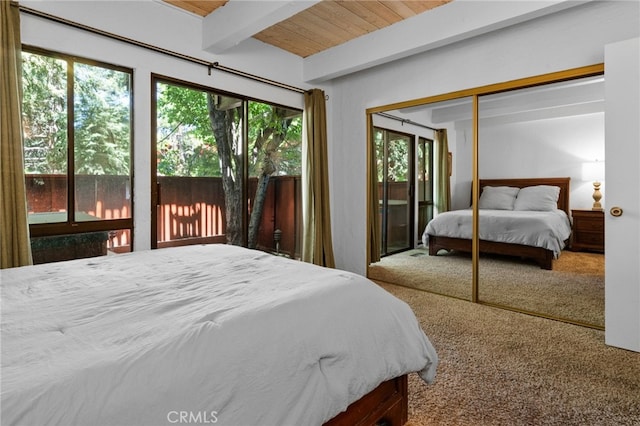 bedroom with beamed ceiling, a closet, carpet flooring, and wooden ceiling