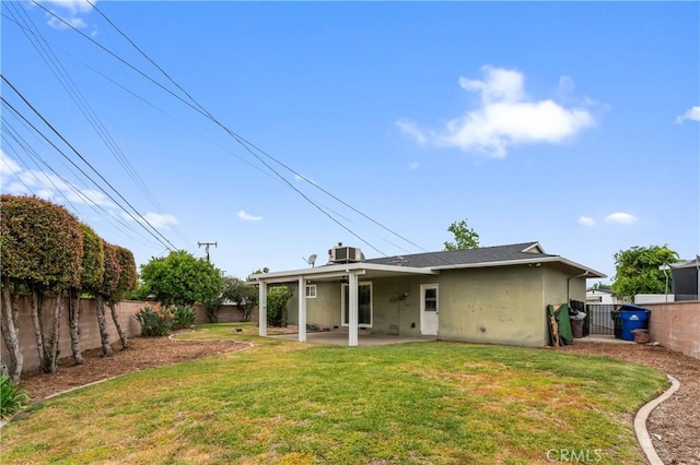 rear view of house featuring stucco siding, a lawn, and a fenced backyard