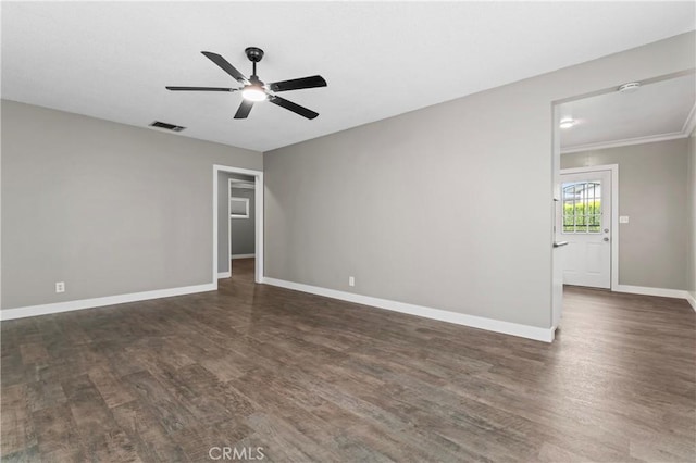 spare room with dark wood finished floors, visible vents, a ceiling fan, and baseboards