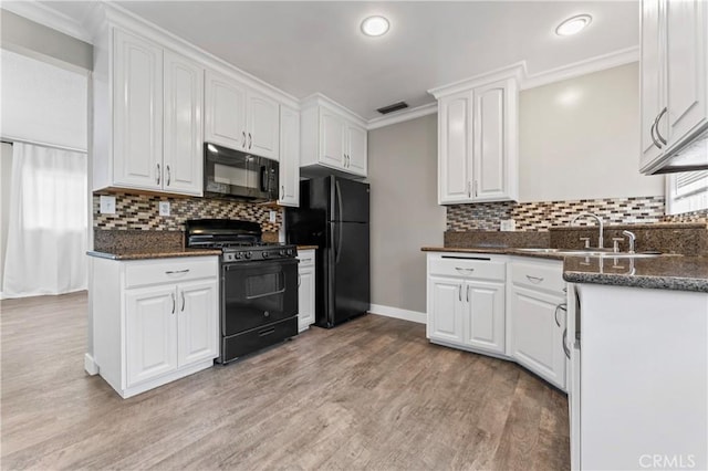kitchen featuring light wood-style flooring, black appliances, backsplash, a sink, and white cabinetry