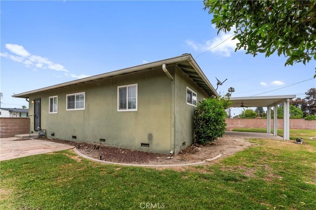 view of side of home featuring fence, a patio area, a yard, and crawl space