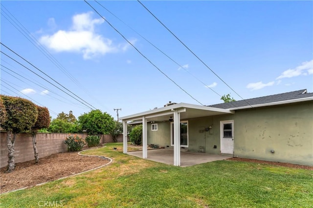 rear view of house featuring a patio area, a fenced backyard, a lawn, a ceiling fan, and stucco siding
