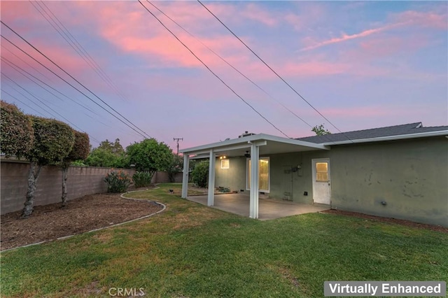 rear view of house with a lawn, stucco siding, a fenced backyard, and a patio area