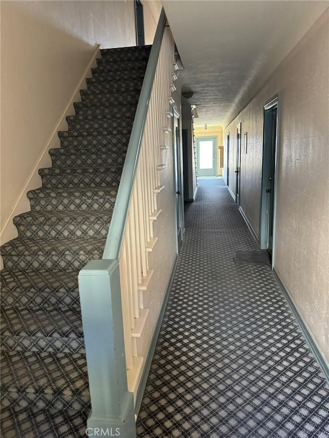 hallway with dark carpet and stairs