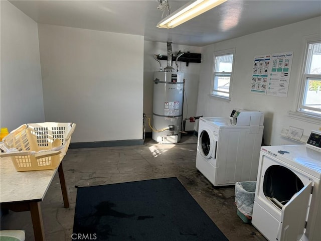 washroom with strapped water heater, washing machine and dryer, and plenty of natural light