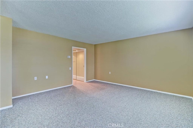 empty room with a textured ceiling, baseboards, and carpet floors