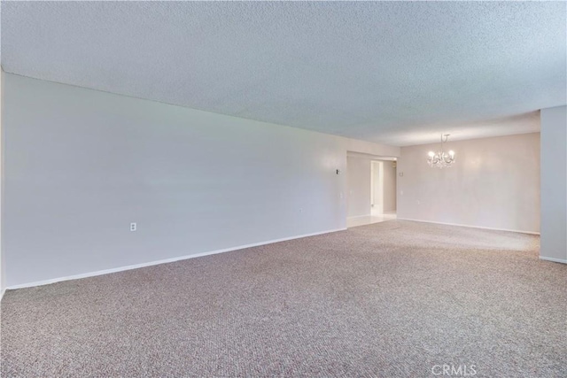 unfurnished room with a chandelier, baseboards, a textured ceiling, and carpet