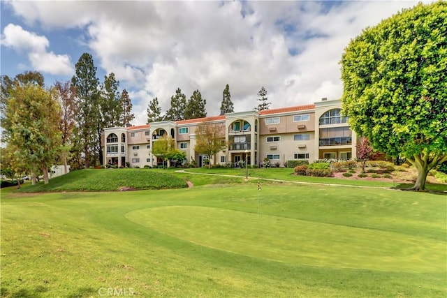 view of home's community featuring a lawn and view of golf course