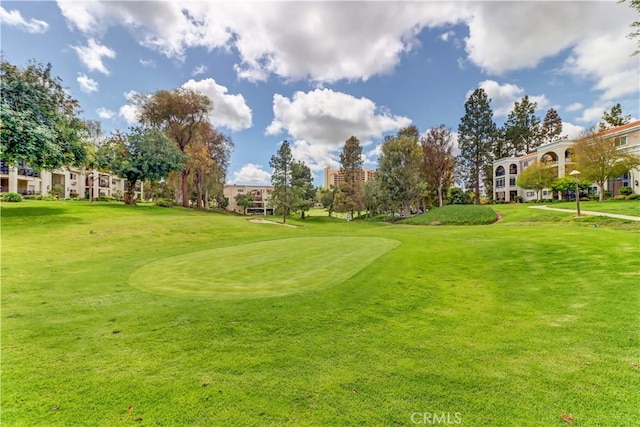 view of community featuring a lawn and view of golf course
