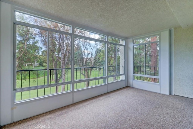 unfurnished sunroom with a textured ceiling, plenty of natural light, and carpet flooring