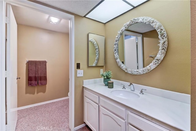 bathroom with toilet, vanity, and baseboards
