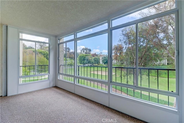 unfurnished sunroom featuring a textured ceiling, carpet flooring, and a wealth of natural light