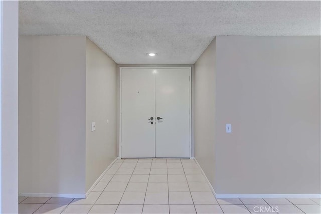 entryway with light tile patterned flooring, a textured ceiling, and baseboards