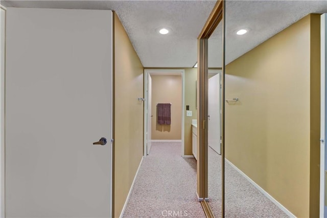 corridor featuring a textured ceiling, recessed lighting, baseboards, and carpet floors