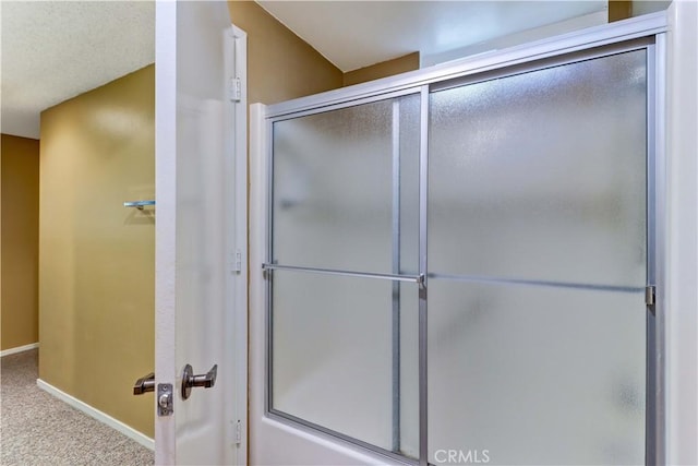 bathroom featuring a shower with door and baseboards