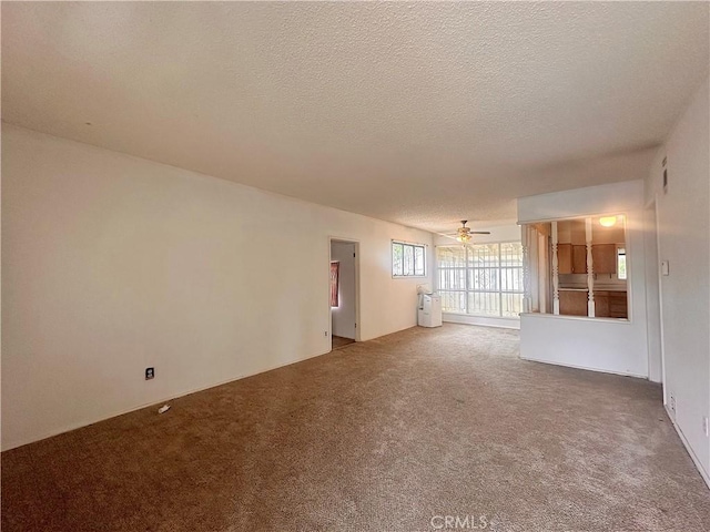 spare room featuring a textured ceiling, carpet flooring, ceiling fan, and visible vents