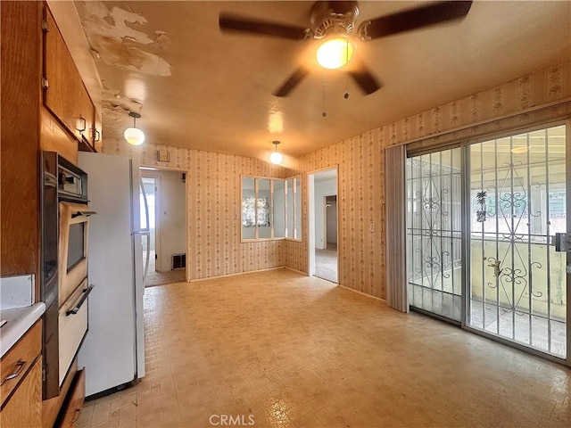 interior space featuring ceiling fan, wallpapered walls, and baseboards
