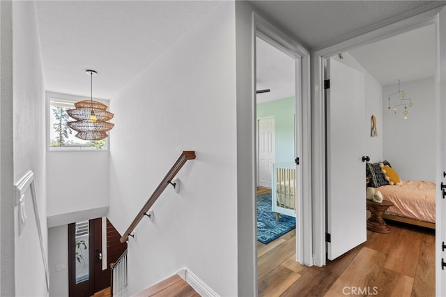 interior space with an upstairs landing, a notable chandelier, and wood finished floors
